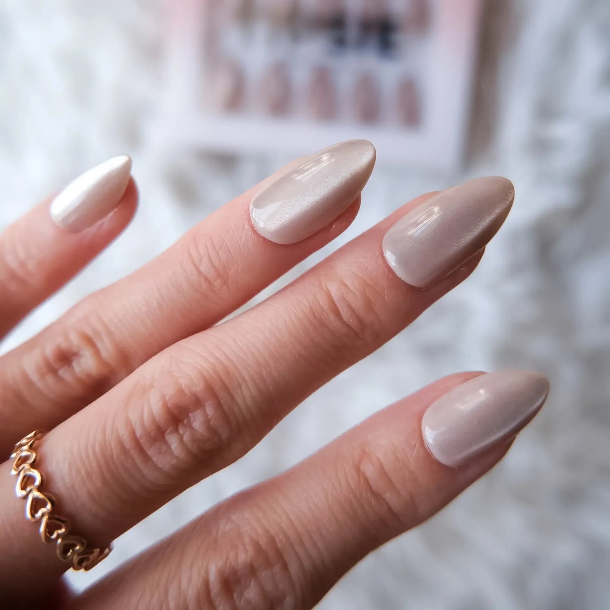 Close-up of a hand with beige nail polish on a blurred background