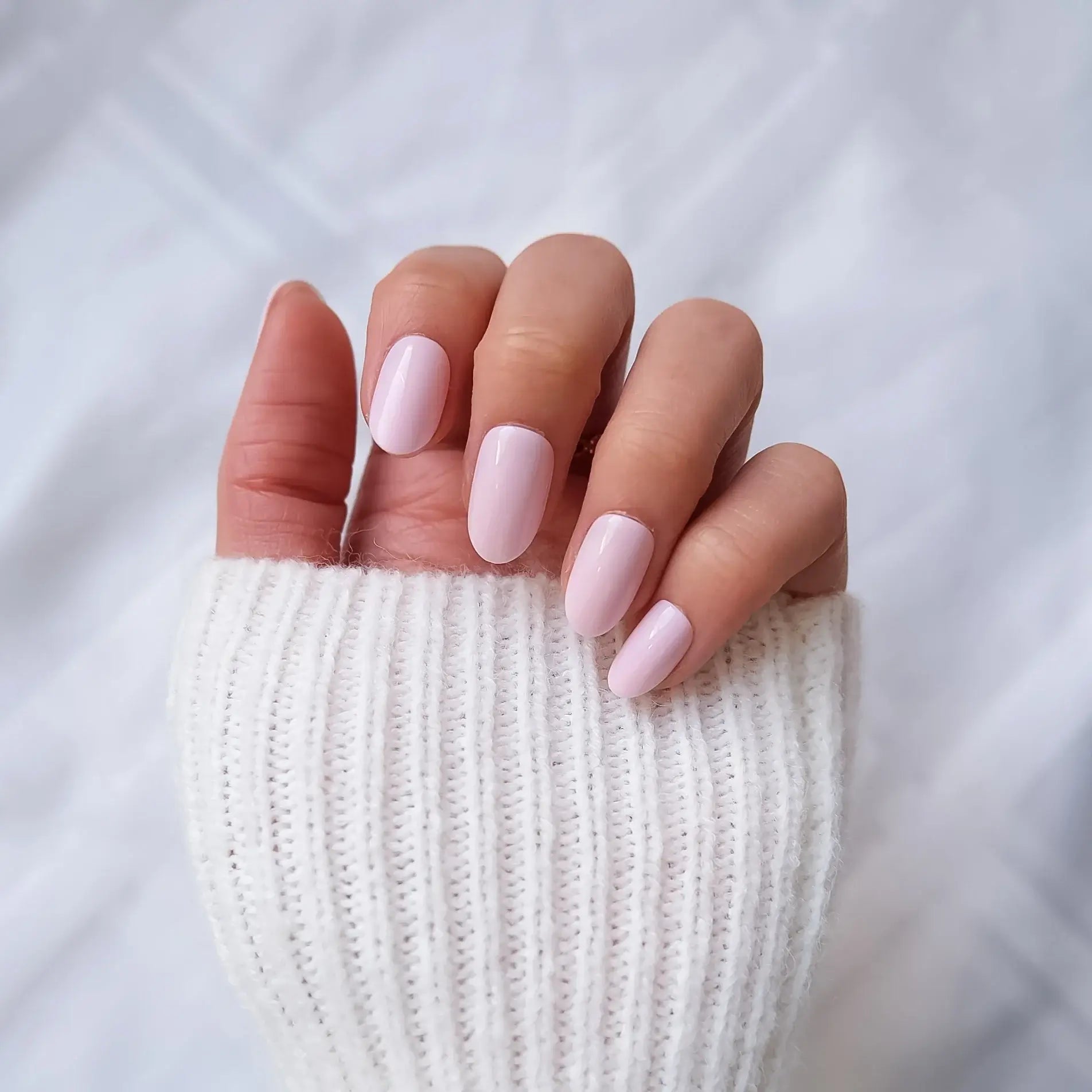 Close-up of a hand with pink nail polish on a white background